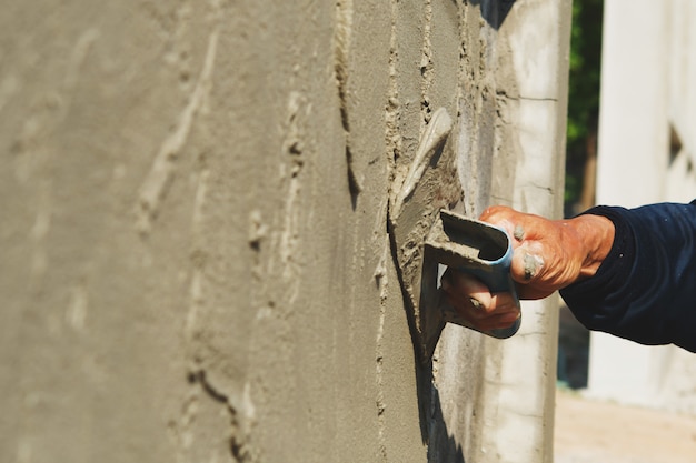 Hand van arbeider het pleisteren cement op muur