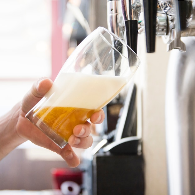 Foto hand van barman die een groot lagerbierbier in kraan gieten