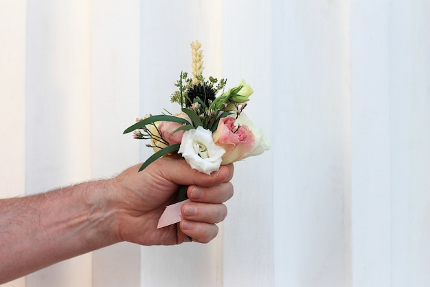 Hand van de man die een klein mooi boeket bloemen houdt