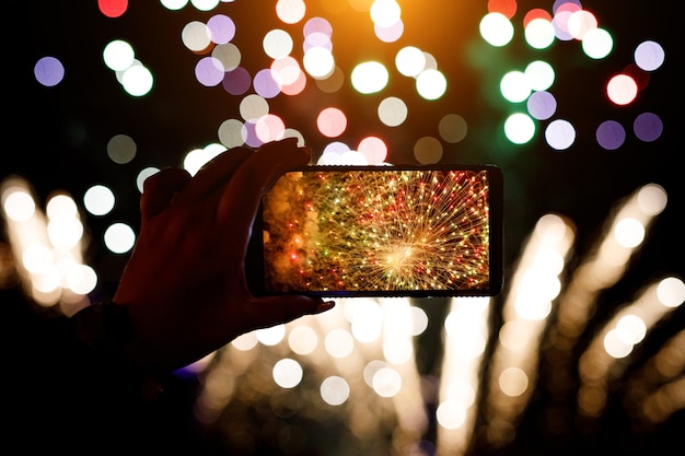 Foto hand van de mens die de foto van vuurwerk neemt door smartphone.