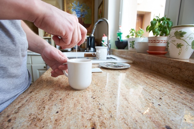 Hand van de witte mens die thee voorbereidt die theezakje gebruikt