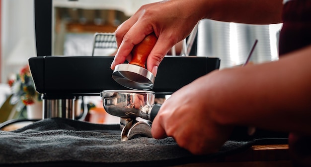 Hand van een barista met een portafilter en een koffiesabotage die een espresso maakt