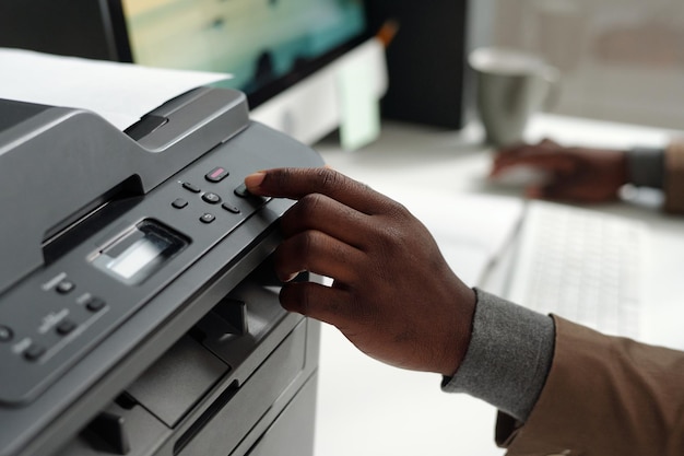 Hand van een jonge Afro-Amerikaanse man die op de knop op het paneel van Xerox drukt
