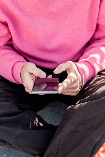 Hand van een jonge man die een mobiele telefoon gebruikt