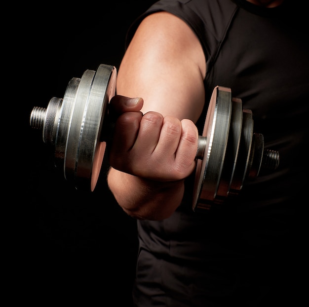 Hand van een man met grote biceps houdt een stalen typerende halter