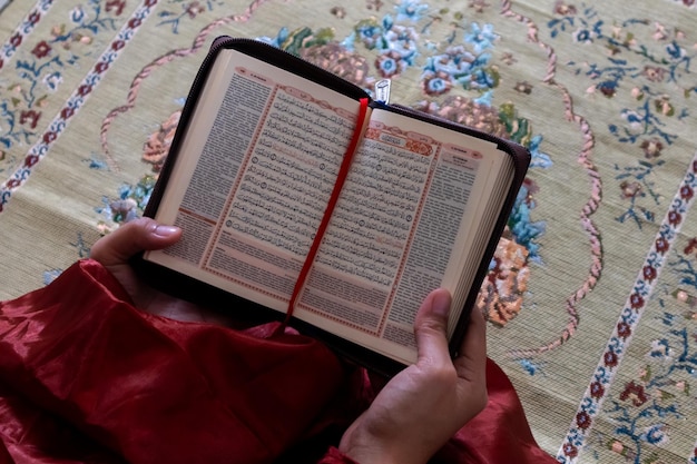 Hand van een moslimvrouw die de koran vasthoudt met een Indonesische vertaling