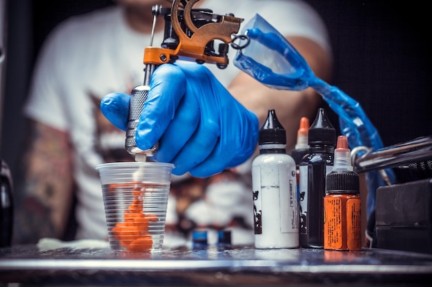 Hand van een professionele tatoeëerder en een tattoo-machine./Hand van een professionele tatoeëerder met een tattoo-machine.