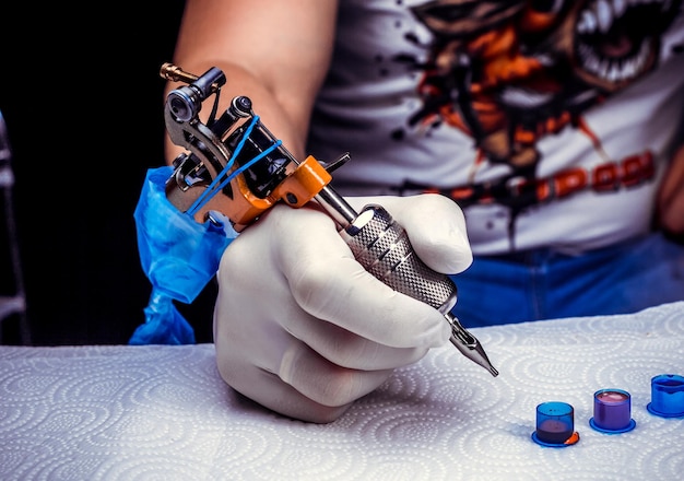 Hand van een tatoeëerder, die de tattoo-machine vasthoudt.