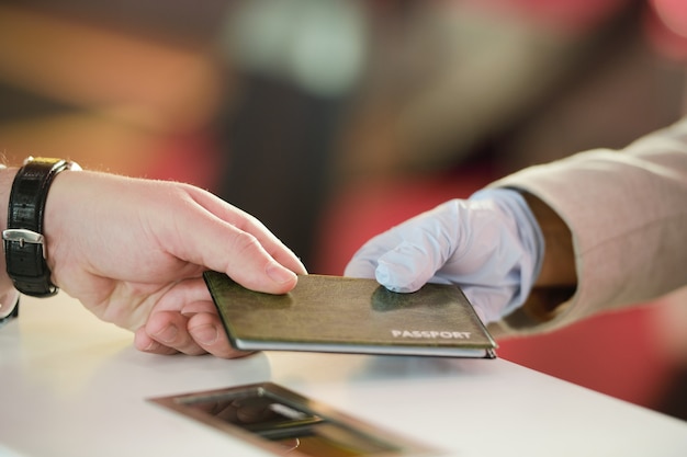 Hand van een volwassen man die zijn paspoort terugneemt na registratie voor de vlucht bij de kassa op de hedendaagse luchthaven