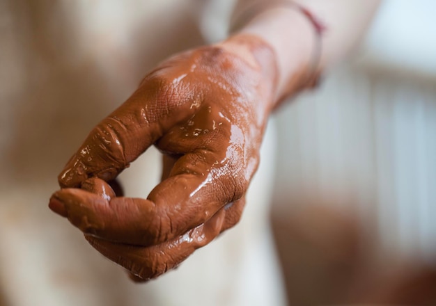 Hand van een vrouwelijke keramiekmaker, hand bedekt met klei.