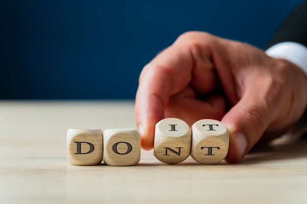 Hand van een zakenman die de laatste twee woorden van Dont sign wegknipt om er een Do it-bericht van te maken.