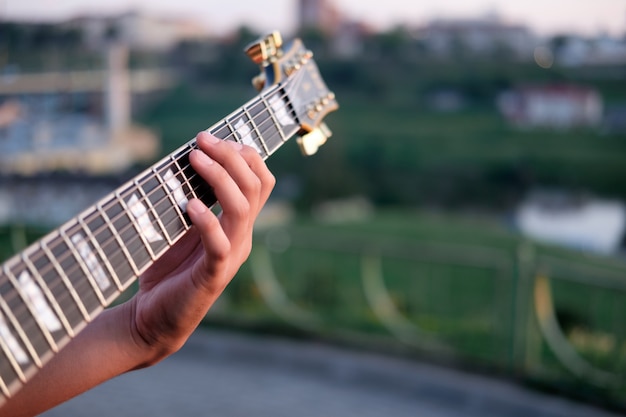 Hand van gitarist die akkoord speelt op een grif van elektrische gitaar,