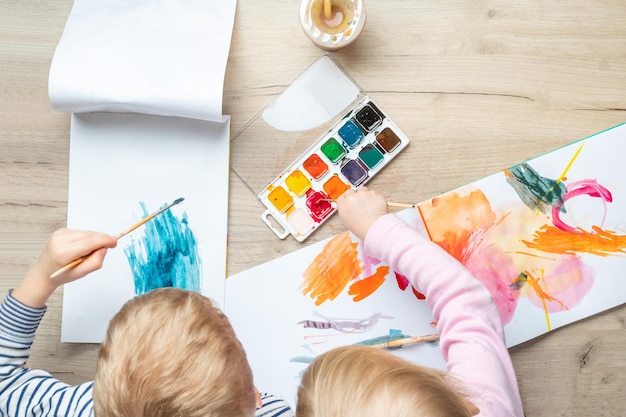 Hand van het kind met penselen tekenen op wit papier Kind tekenen bovenaanzicht