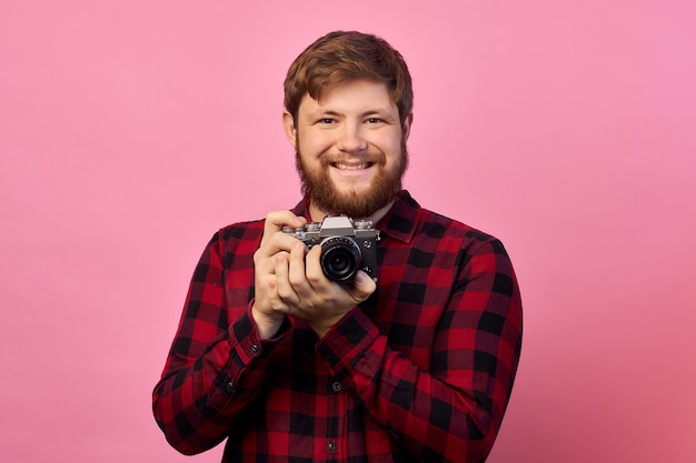 Hand van jonge Spaanse man met vintage camera over geïsoleerde roze achtergrond