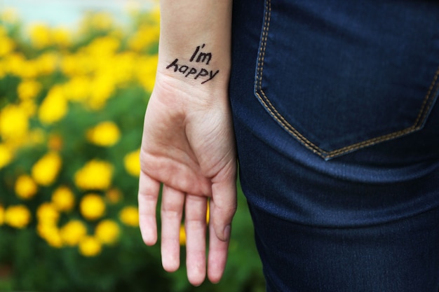 Hand van jonge vrouw met getatoeëerde zin erop, op bloemen, close-up