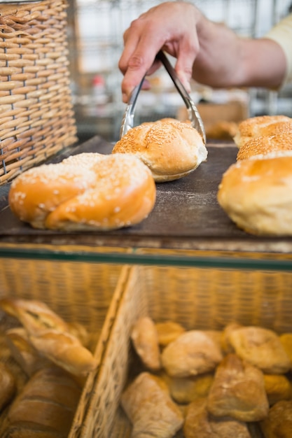 Hand van kelner die brood met tang neemt