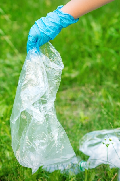 Hand van kind reinigt het park van plastic afval dat op het groene gras ligt