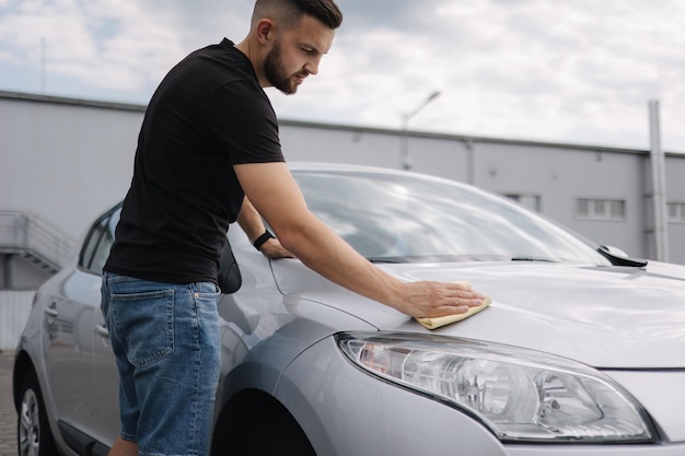 Hand van man veegt koplamp van zijn auto af met behulp van tapijt selfservice carwash buiten