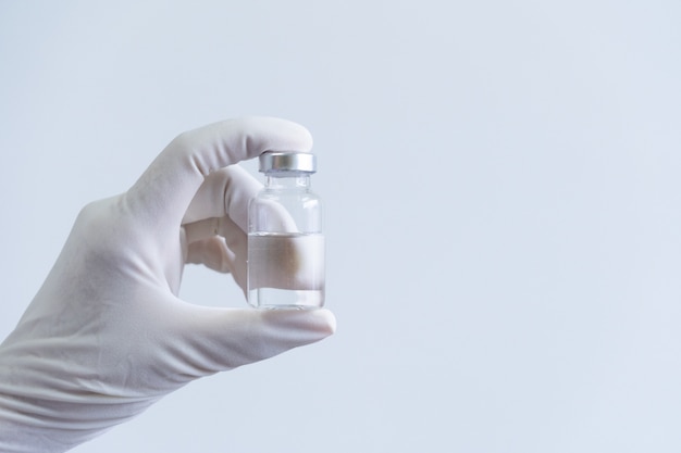 Foto hand van medisch personeel in pbm-pak en vaccins voor de behandeling van virusziekte