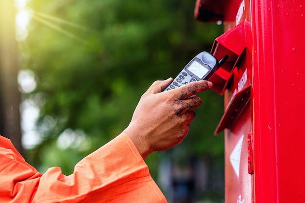 Hand van meisje die de oude mobiel houden en in postbus zetten