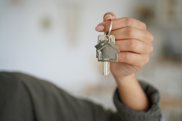 Hand van meisje houdt sleutel van nieuw huis Hypotheeklening en onroerendgoedaankoop makelaarsbedrijf