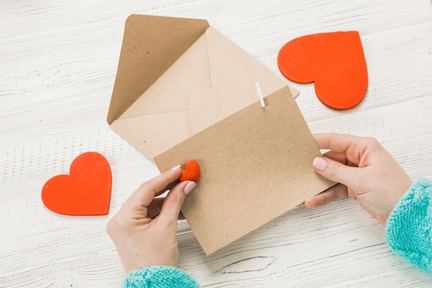 Hand van meisje liefdesbrief schrijven op Saint Valentines Day. Handgemaakte ansichtkaart met rood hartvormig figuur. 14 februari vakantieviering. Valentine dag concept met kopie ruimte.