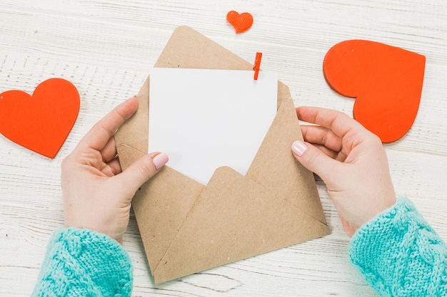 Hand van meisje liefdesbrief schrijven op Saint Valentines Day handgemaakte ansichtkaart met rood hartvormige figuur 14 februari vakantie viering Valentine dag concept met kopie ruimte