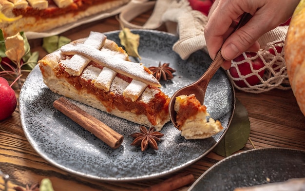 Hand van persoon breekt een stuk smakelijke taart af met een lepel Concept van een warme en gezellige herfstsfeer met de geur van vers lekker gebak