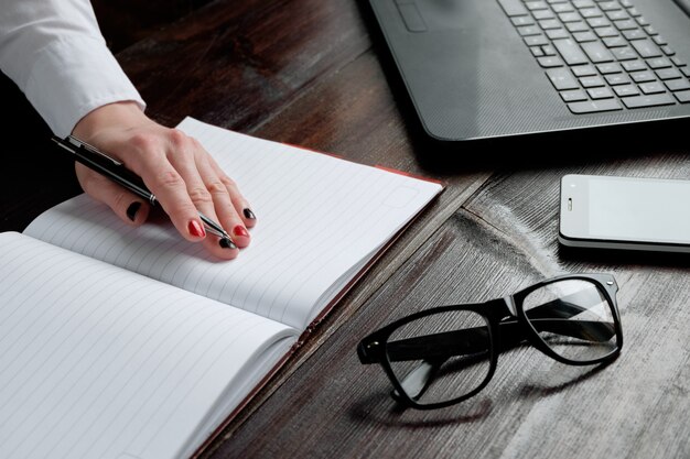 Hand van vrouw die in notitieboekje schrijft