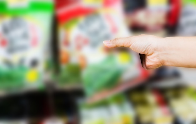 hand van vrouw kiezen of nemen van zoete producten, snacks op planken in supermarkt