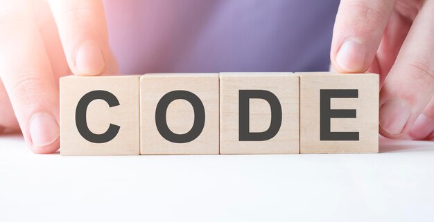 Hand van zakenman met houten kubusblok met CODE zakelijk woord op tafel achtergrond