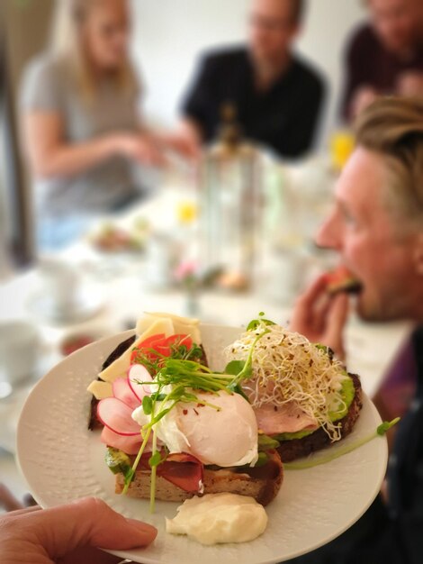 Foto hand vasthouden aan eten met mensen die in een restaurant eten