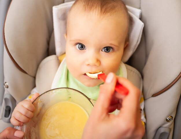 Hand voedt zorgvuldig een schattig gezond pasgeboren meisje met babyvoeding