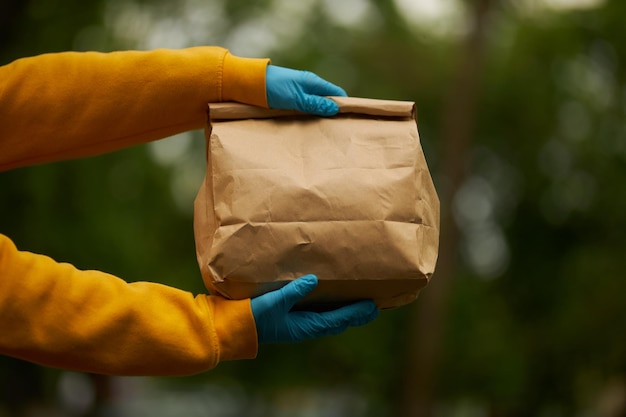 Hand of a volunteer closeup on a street background with a paper bag