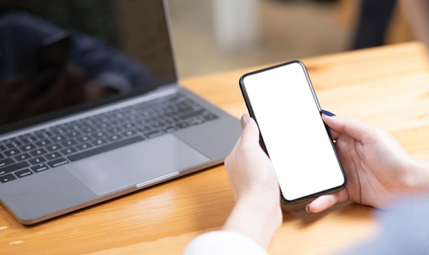 Hand vrouw met behulp van een telefoon leeg scherm slimme telefoon en computer op houten tafelblad weergave