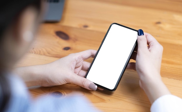 Hand vrouw met behulp van een telefoon leeg scherm slimme telefoon en computer op houten tafelblad weergave