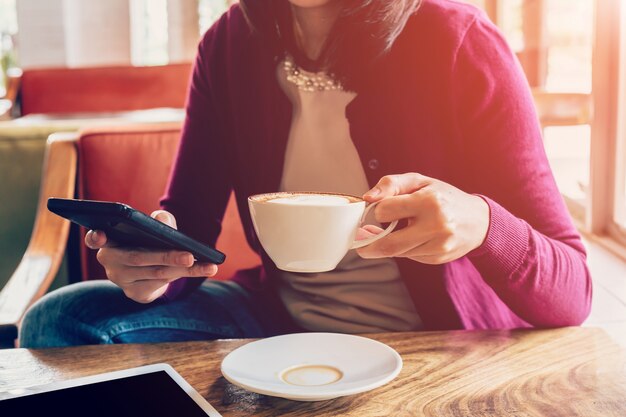 hand vrouw met telefoon en cup in koffie winkel met vintage Toon.