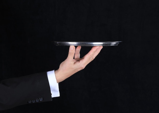 Photo hand of a waiter with a tray on a black background