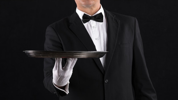 Hand of a waiter with a tray on a black background