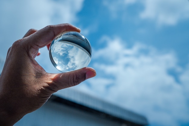 Photo the hand was holding a glass ball and shone at the blue sky.