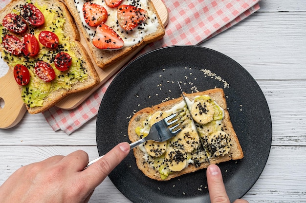 The hand was using a knife and fork to cut the banana toast