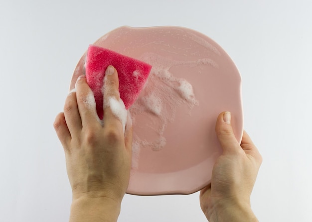 Hand washes a plate with a sponge