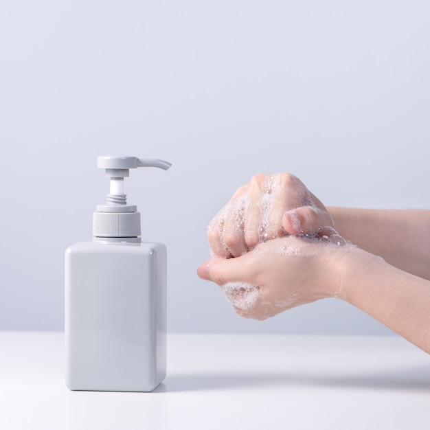 Hand wassen. Aziatische jonge vrouw die vloeibare zeep gebruikt om handen te wassen, concept van hygiëne om te stoppen met het verspreiden van coronavirus geïsoleerd op grijs witte achtergrond, close-up.