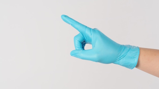 手は青い医療用手袋を着用し、白い背景にポイントまたはタッチまたはプッシュジェスチャーを行います。
