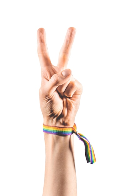 Hand wearing a bracelet with the colors of the LGBT flag showing two fingers as a symbol of peace