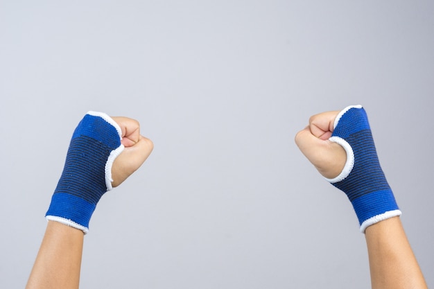 Hand wearing elastic hand and wrist support with clenched fist as fighting gesture