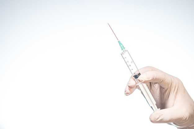 Photo hand wearing latex glove holding syringe with a medicine on white