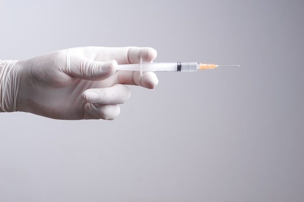 Hand wearing latex glove holding syringe with a medicine