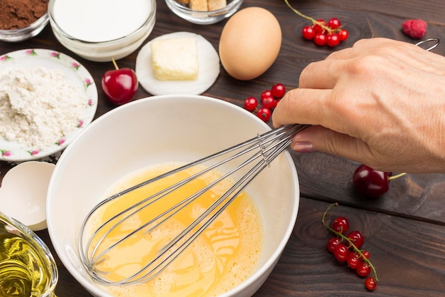 Foto uova battute a mano in una ciotola con battuta farina di bacche di latte ingredienti per la cottura della colazione close up