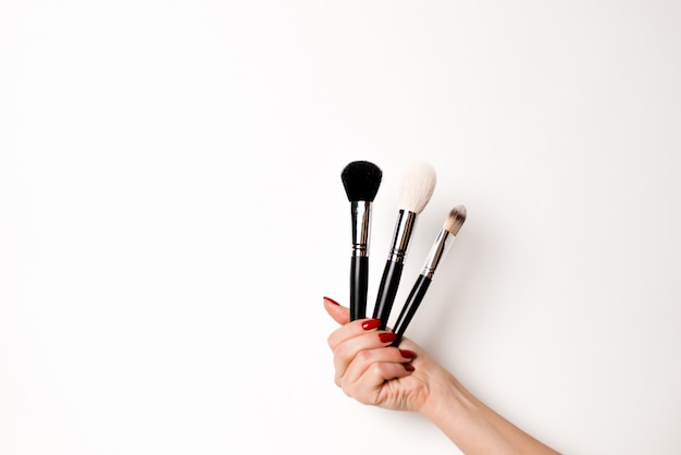 Hand on a white background keeps makeup brushes